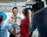 Camera Recording Video Of Businessman Corporate Interview And Makeup Artist Happy businessman during corporate interview with journalist. Vip or manager talking and smiling in office. Woman at work as makeup artist with business man and cameraman shooting video with camera