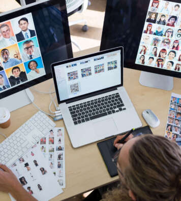 Male executive working over laptop and graphic tablet at his desk in office