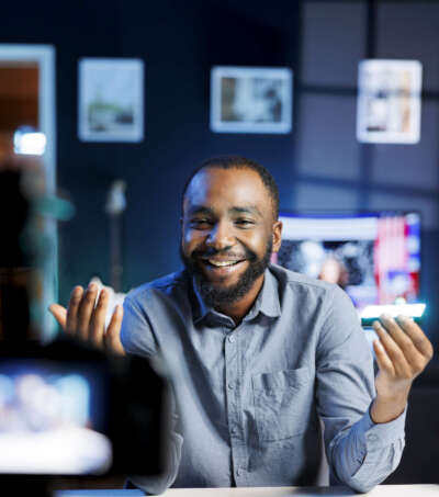 Cheerful internet show host reviewing mini RGB lights, satisfied with special effects modes options. Media star excited about excellent adjustable colors on video production tool