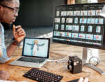 Two photographers working on the computers in the studio Two male photographers choosing woman's portraits at the working place with two computers in the studio